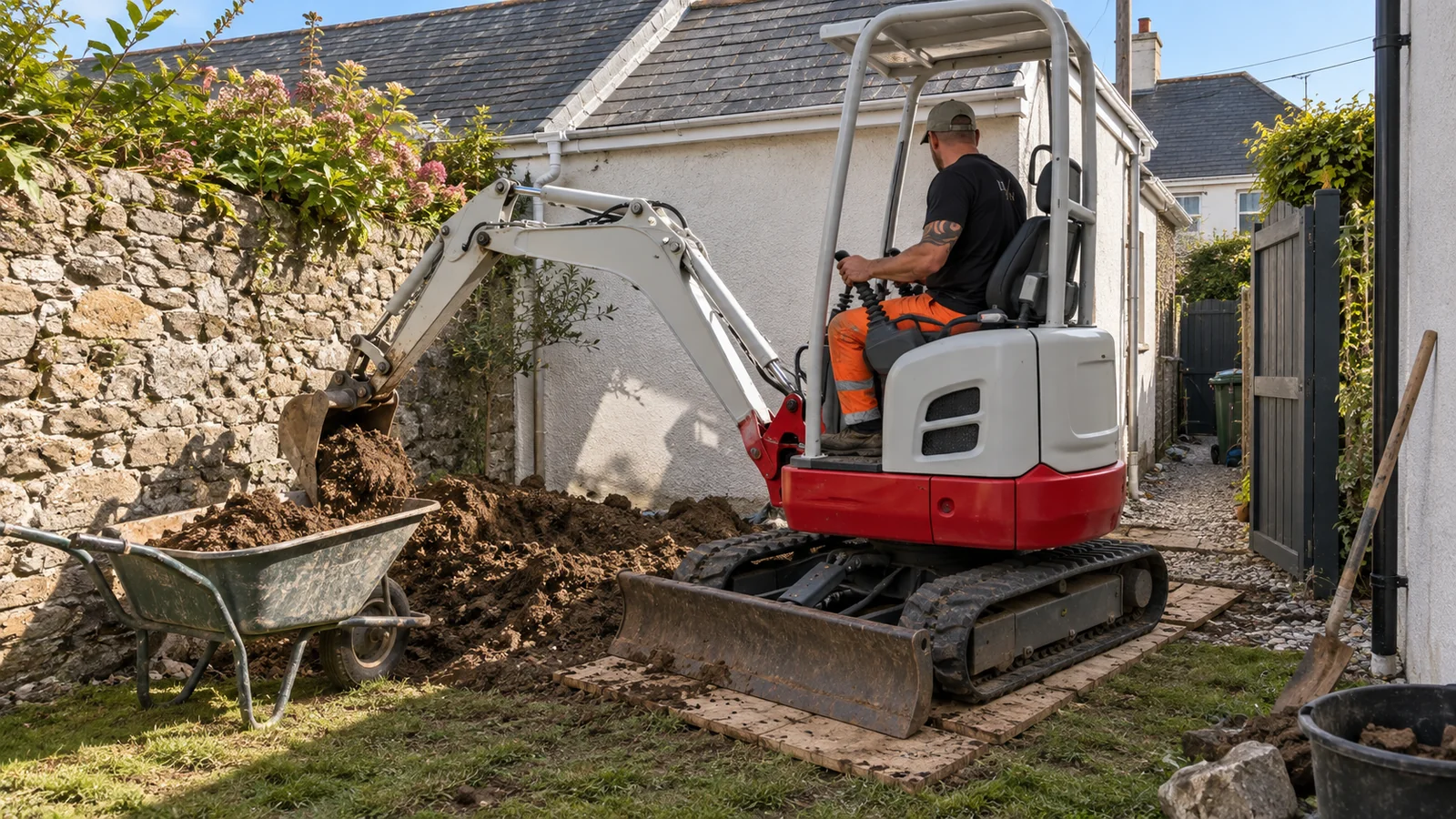 Mini digger being operated to excavate a trench in a west Cornwall garden with a dumper alongside
